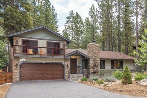 A two-story house with a stone chimney, a balcony, and a garage. - Walk to Summit. Relaxing Spa and Fireplace. (Big Bear)