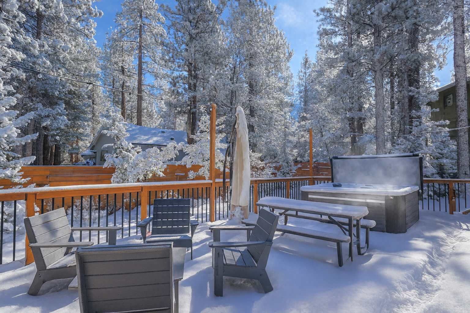 Una terraza cubierta de nieve con mobiliario exterior y una bañera de hidromasaje.
