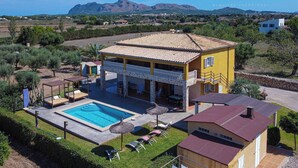 Una vila groga amb piscina, mobiliari exterior i vistes a les muntanyes.