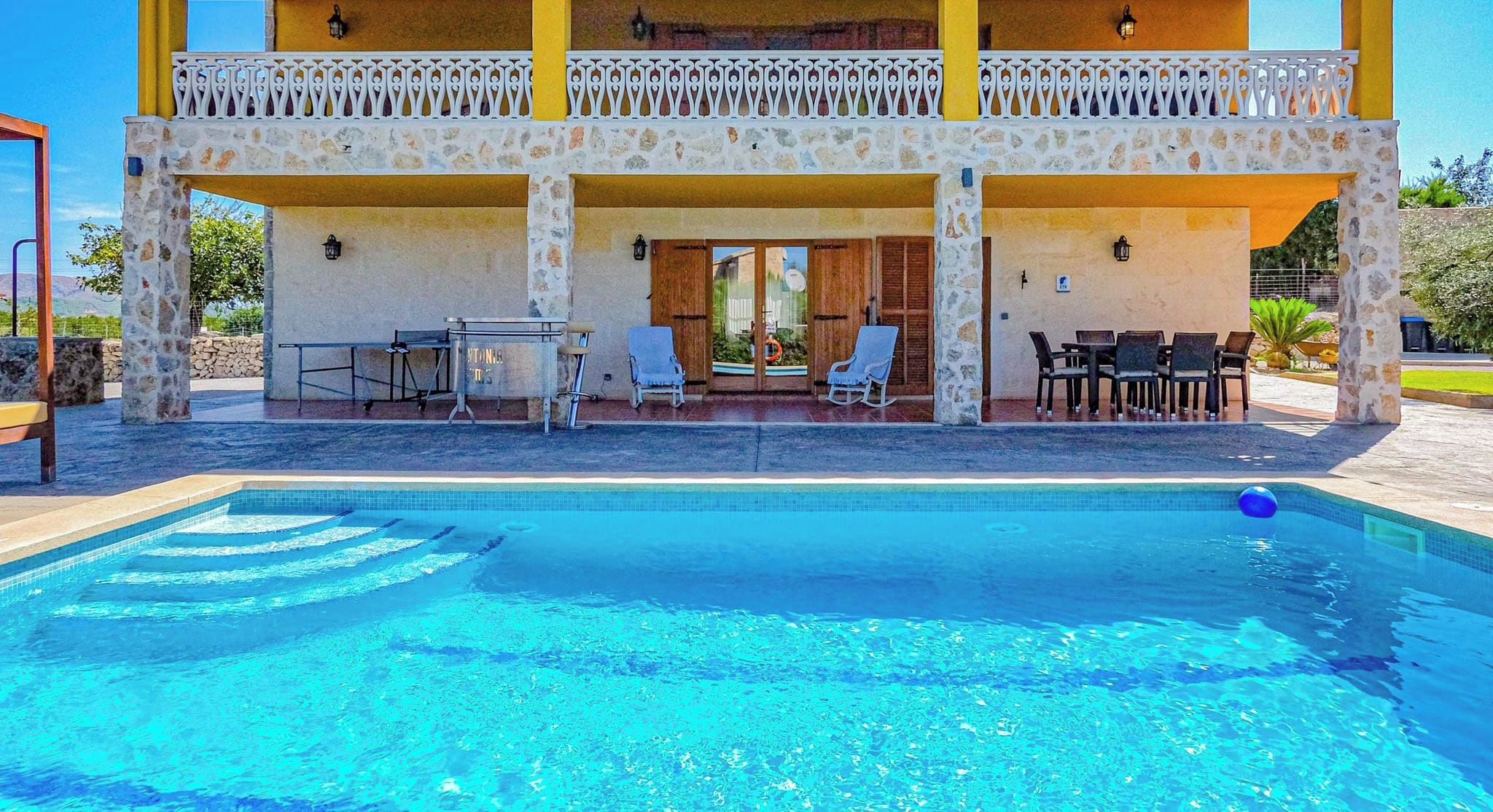 Un edificio de dos pisos con una piscina en la parte delantera.