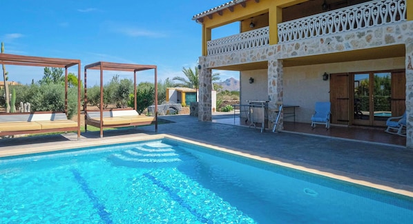 Ein zweistöckiges Gebäude mit Pool, Sitzgelegenheiten im Freien und einem Balkon.