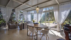 Una habitación iluminada por el sol con una mesa de comedor, sillas, sofás y vistas a un jardín.