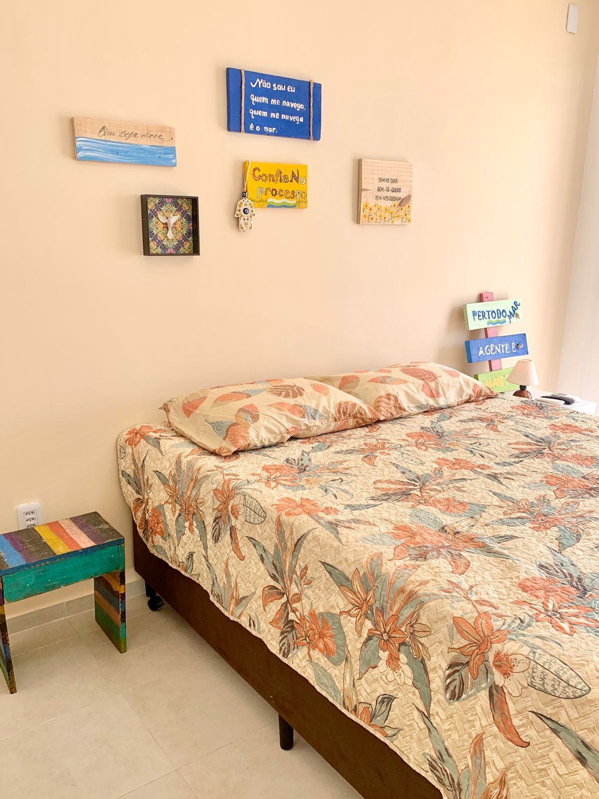 Un dormitorio con cama, una mesita y adornos en la pared.