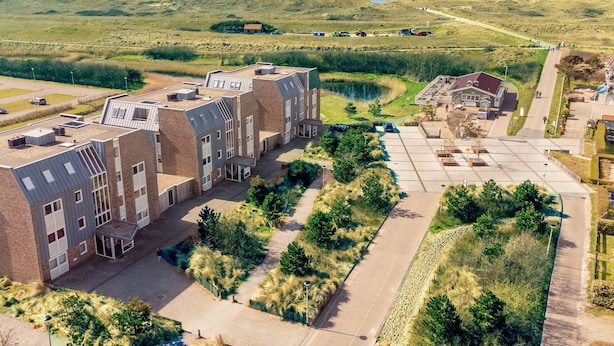Un ensemble immobilier moderne comprenant plusieurs bâtiments, des aires de stationnement et offrant une vue sur le paysage environnant.