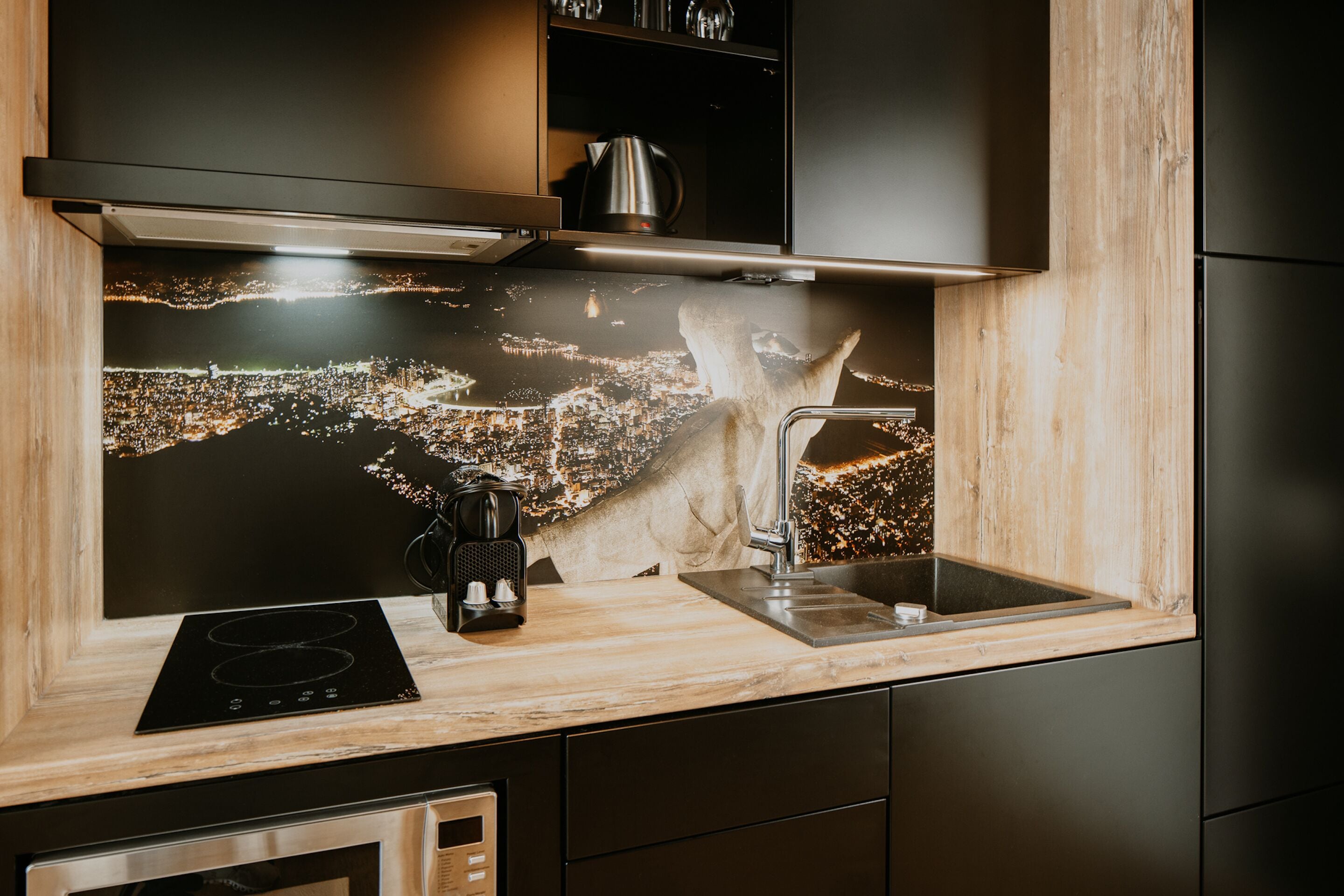 Une cuisine moderne avec un dosseret représentant un paysage urbain, des appareils en acier inoxydable et des meubles de cuisine en bois.