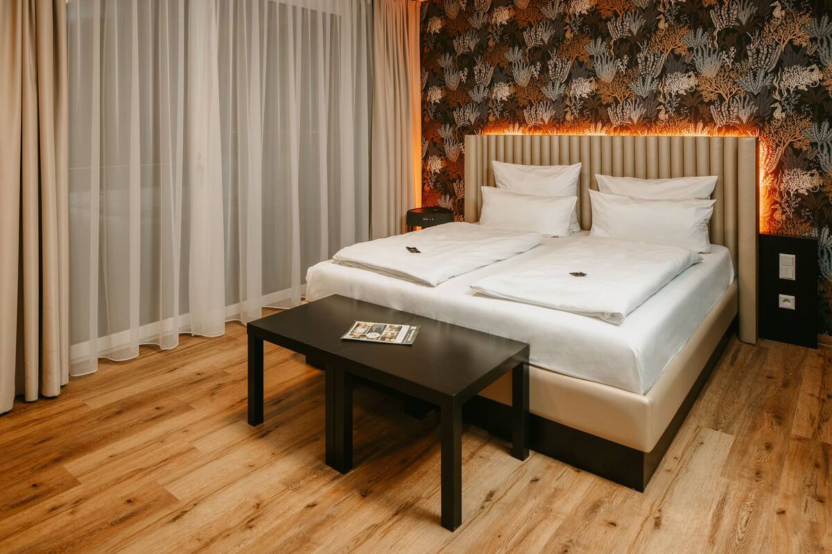 A neatly made bed with a headboard, a bedside table, and a nightstand.