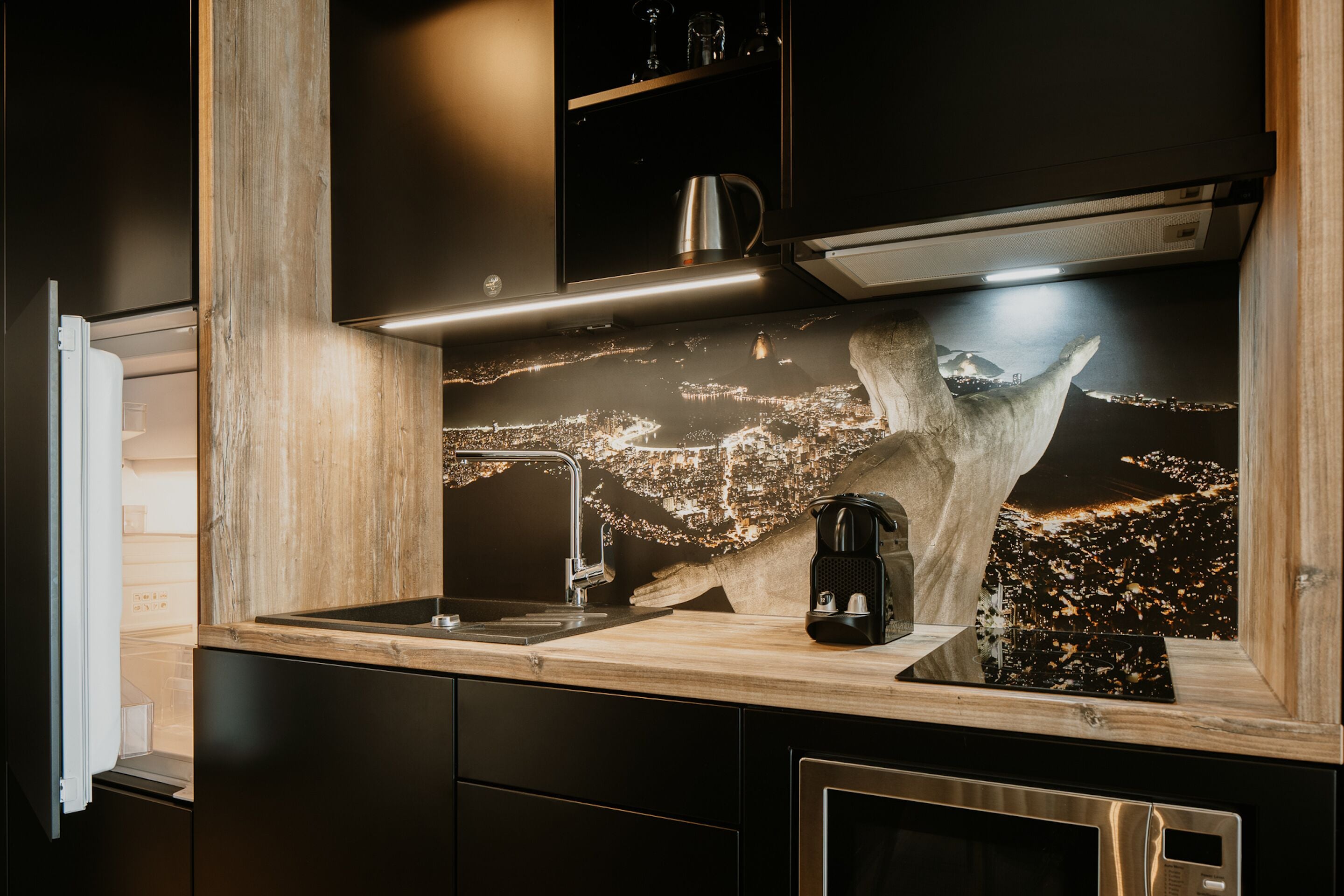 A modern kitchen with a wooden countertop, stainless steel appliances, and a cityscape backsplash.