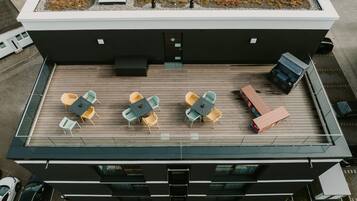 A rooftop terrace with outdoor seating and a modern building design.