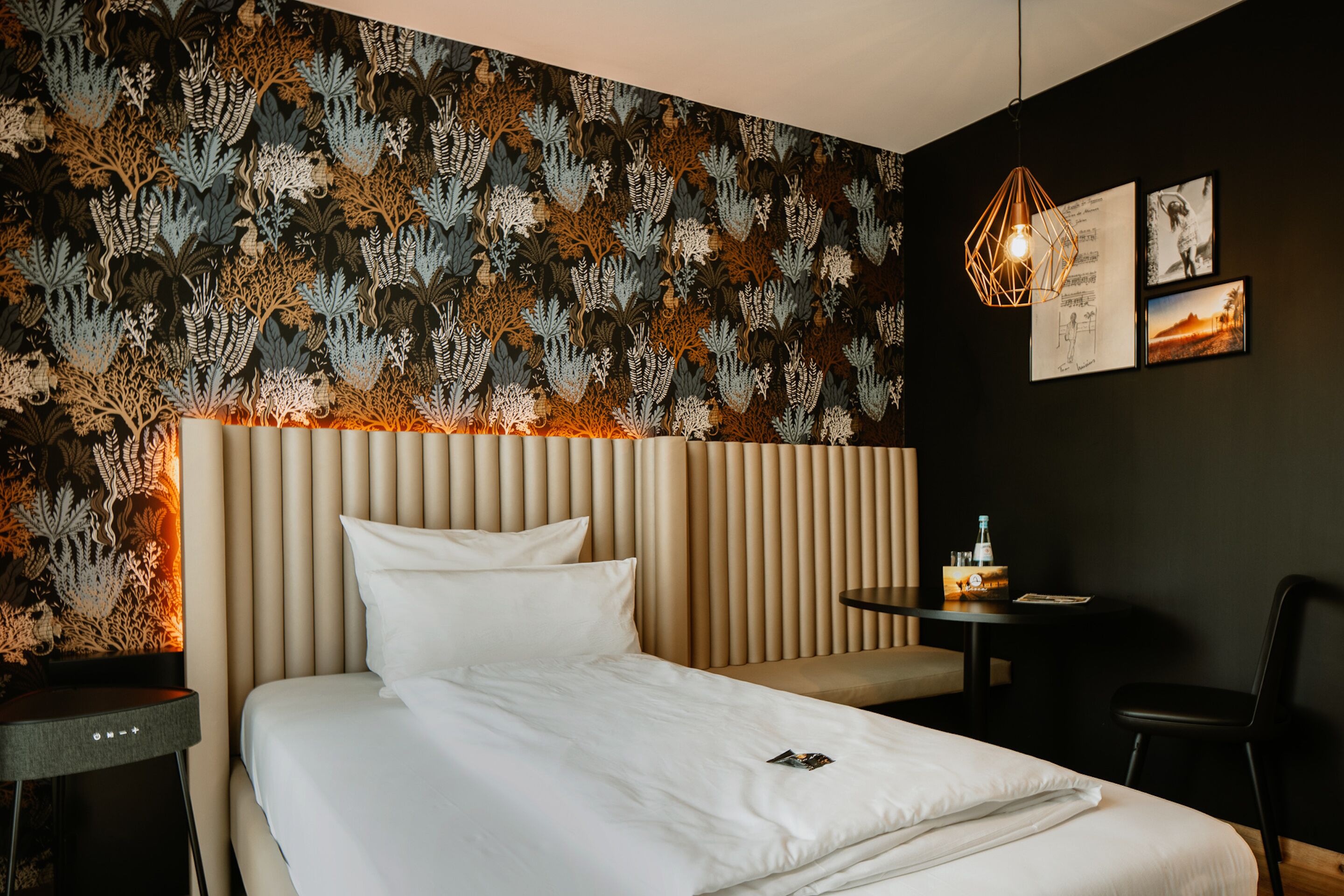 Ein modernes Hotelzimmer mit einem großen Bett, einem Nachttisch, einem kleinen Schreibtisch und einem Sessel.