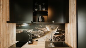 Une cuisine moderne avec un plan de travail décoré d’un motif représentant un paysage urbain, une plaque de cuisson intégrée et un évier.