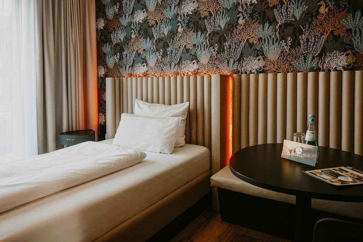 A hotel room with a bed, bedside table, and a round table with a menu.