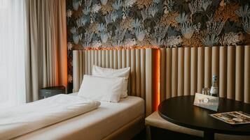 Une chambre d’hôtel avec un lit, une table de chevet et une table ronde sur laquelle est posé un menu.