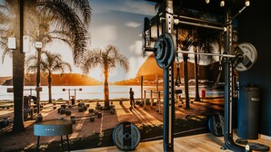 Une salle de sport avec vue sur la plage et le coucher de soleil.