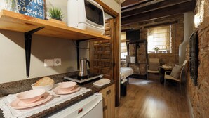 Eine Küche mit Mikrowelle, Toaster und Kaffeemaschine auf der Arbeitsfläche, einem Holzregal darüber und einem Essbereich mit Tisch und Stühlen.