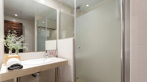 Ein modernes Badezimmer mit einer gläsernen Duschkabine, einem Waschbecken mit Spiegel darüber und einem Schild mit der Aufschrift 'Smile Every Day Get It Over With'.