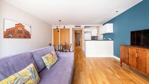 A modern living room with a purple sofa, wooden cabinet, and a TV. - Central apart 1 room near beaches with parking (Barcelona)