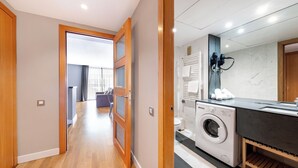 A modern apartment with a hallway leading to a living area, a compact kitchen with a washing machine, and a bathroom with a towel rack. - Central apart 1 room near beaches with parking (Barcelona)