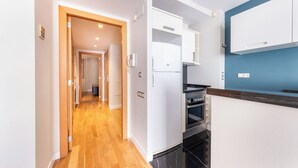 A modern kitchen with white cabinets, a black oven, and a blue accent wall. - Central apart 1 room near beaches with parking (Barcelona)