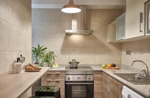 A modern kitchen with a built-in oven, a stainless steel range hood, and a granite countertop. - Great 3-bedroom apartment ideal for families near Sants Station (Barcelona)