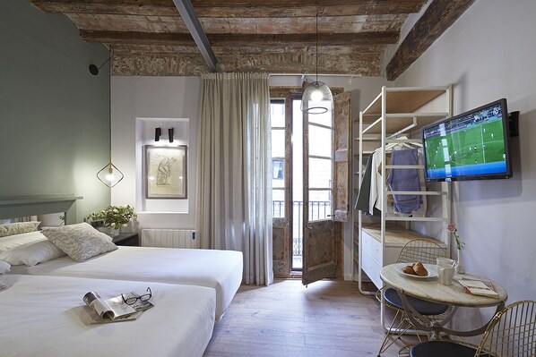 Une chambre d’hôtel avec un lit, une table de chevet, un téléviseur fixé au mur, une fenêtre avec des rideaux et une vue sur l’extérieur.