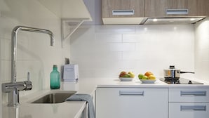 Une cuisine moderne avec des meubles blancs, des appareils en acier inoxydable et un saladier de fruits posé sur le plan de travail.
