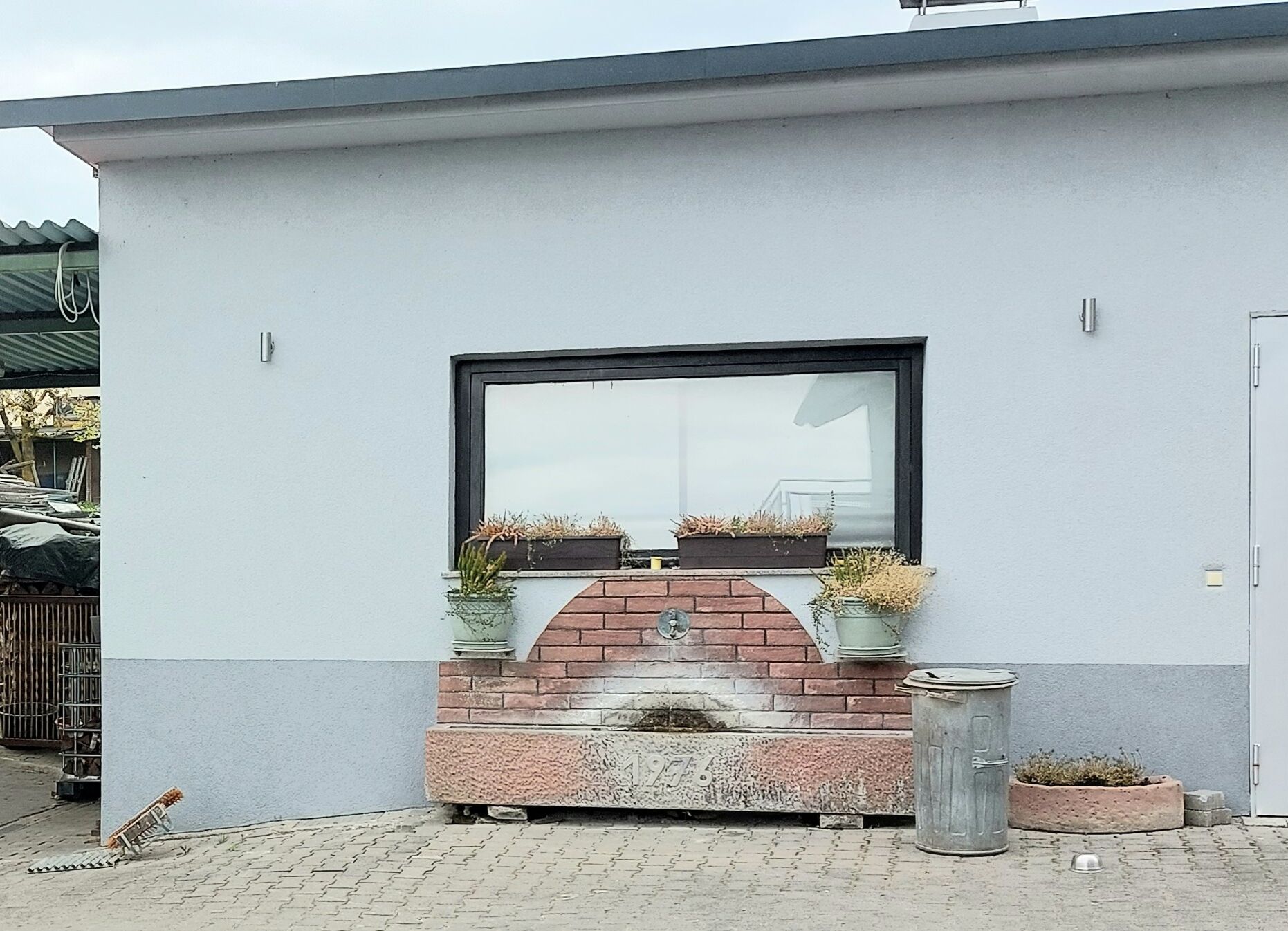 A modern building with a large window, a brick fireplace, and potted plants.