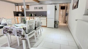 A compact living space with a dining area, kitchenette, and a shower area. - 3 person vacation apartment in the countryside with plenty of space to linger (Mörlenbach)