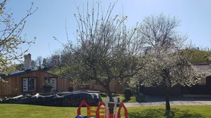 A playground with a slide and swings, a wooden house, and a tree with blossoms. - 3 person vacation apartment in the countryside with plenty of space to linger (Mörlenbach)