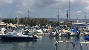 A marina with various boats docked, a clear sky, and a distant view of hills. - 2 Bedroom Ground Floor Apartment Close to Shops, Restaurants, Old Town and beach (Paphos)