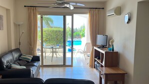 A living room with a sofa, TV, and a dining area with a table and chairs. - 2 Bedroom Ground Floor Apartment Close to Shops, Restaurants, Old Town and beach (Paphos)