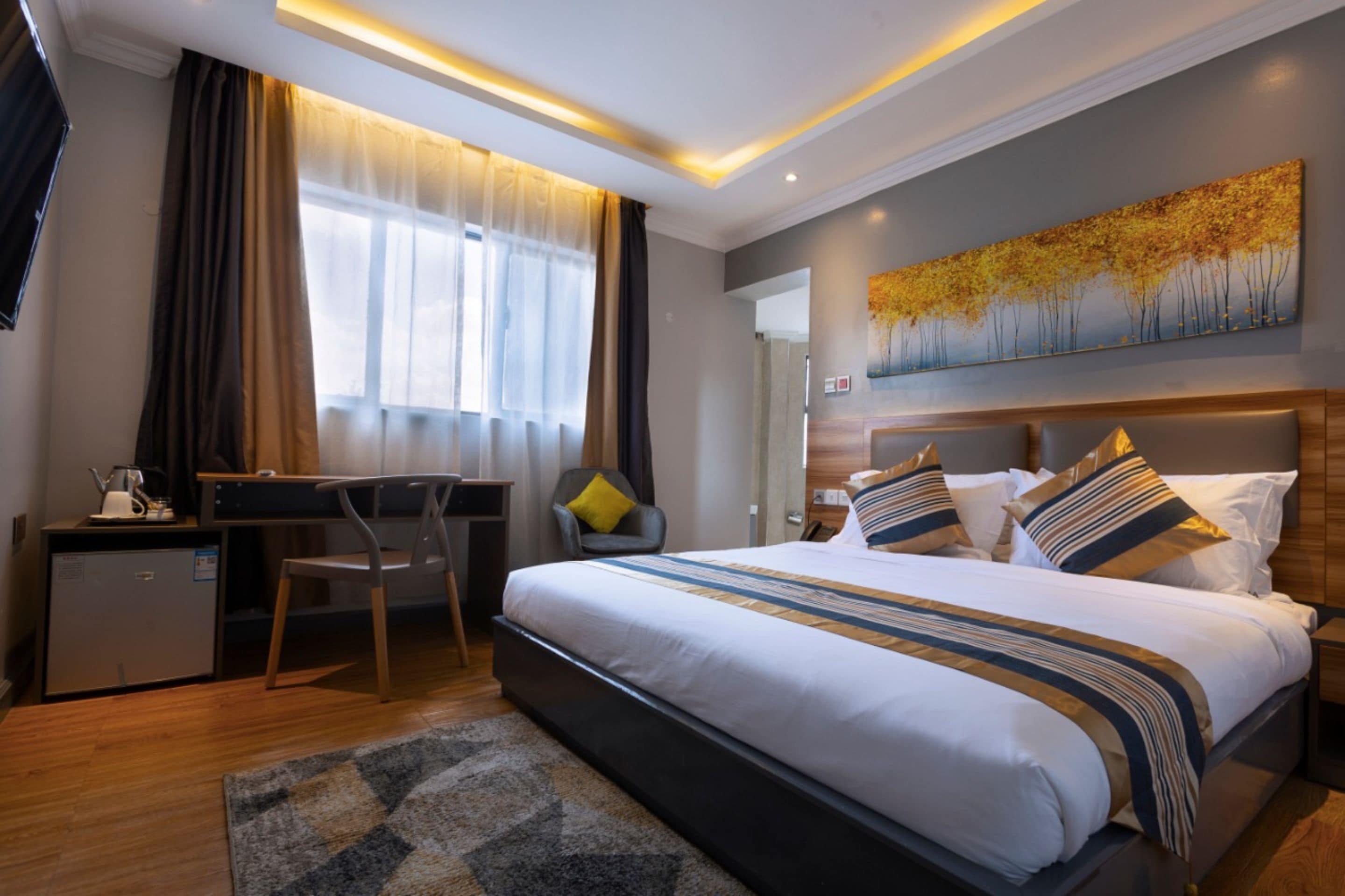 A modern hotel room with a large bed, a desk, and a chair.