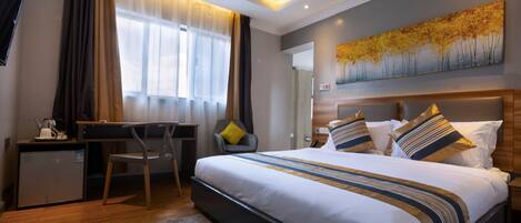 A modern hotel room with a large bed, a desk, and a chair.