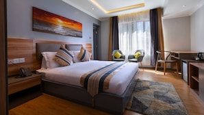 Ett modernt hotellrum med en stor säng, ett skrivbord och en stol.
