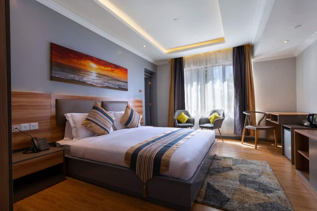 A modern hotel room with a large bed, a desk, and a chair.