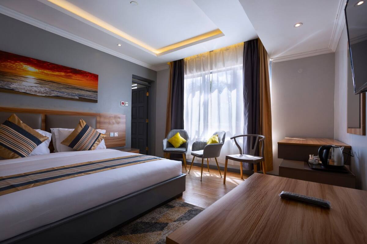A modern hotel room with a large bed, a desk, and a chair.