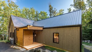 Eine moderne Holzhütte mit Holzfassade, Metall-Dach und einer kleinen Veranda.