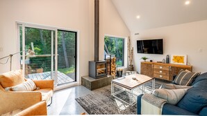 Ein modernes Wohnzimmer mit Kamin, einer Couch, einem Couchtisch und einem Fernseher.