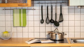 Une cuisine équipée d’une cuisinière, avec une casserole sur le feu, et divers ustensiles de cuisine accrochés au mur.