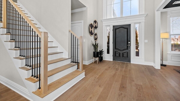 Un'ampia hall con una scala in legno, una porta nera e una grande finestra.