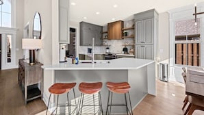 Una cucina moderna con un'isola grande, sgabelli da bar e un'area pranzo con tavolo e sedie.
