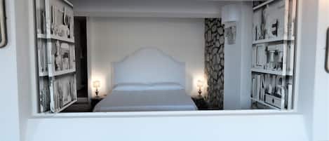 A bedroom with a large bed, two bedside tables with lamps, and a stone accent wall.