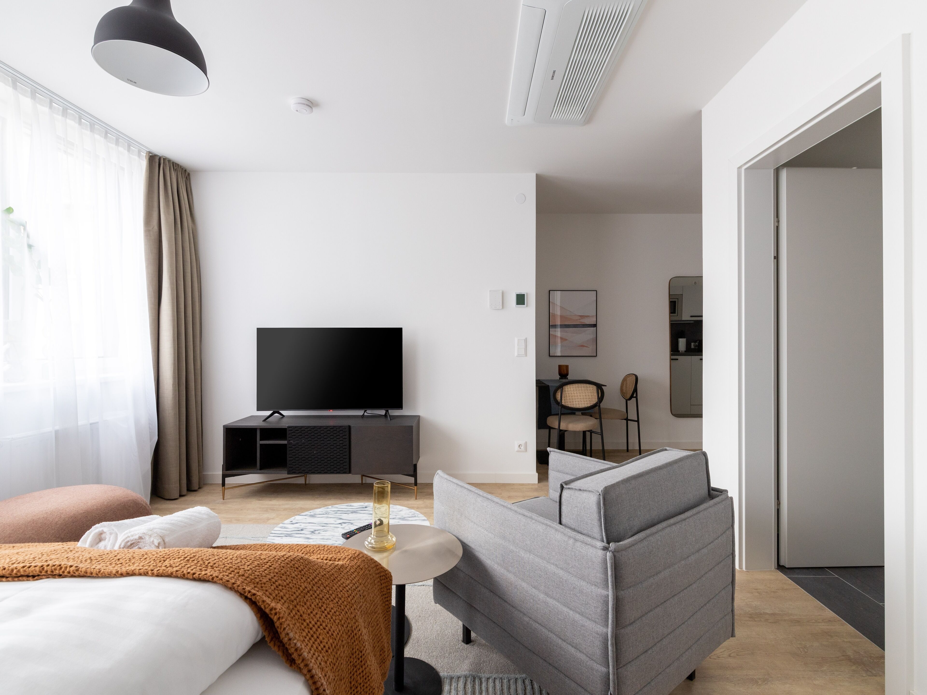 Ein modernes Hotelzimmer mit Bett, einer Couch, einem Fernseher und einem Essbereich.