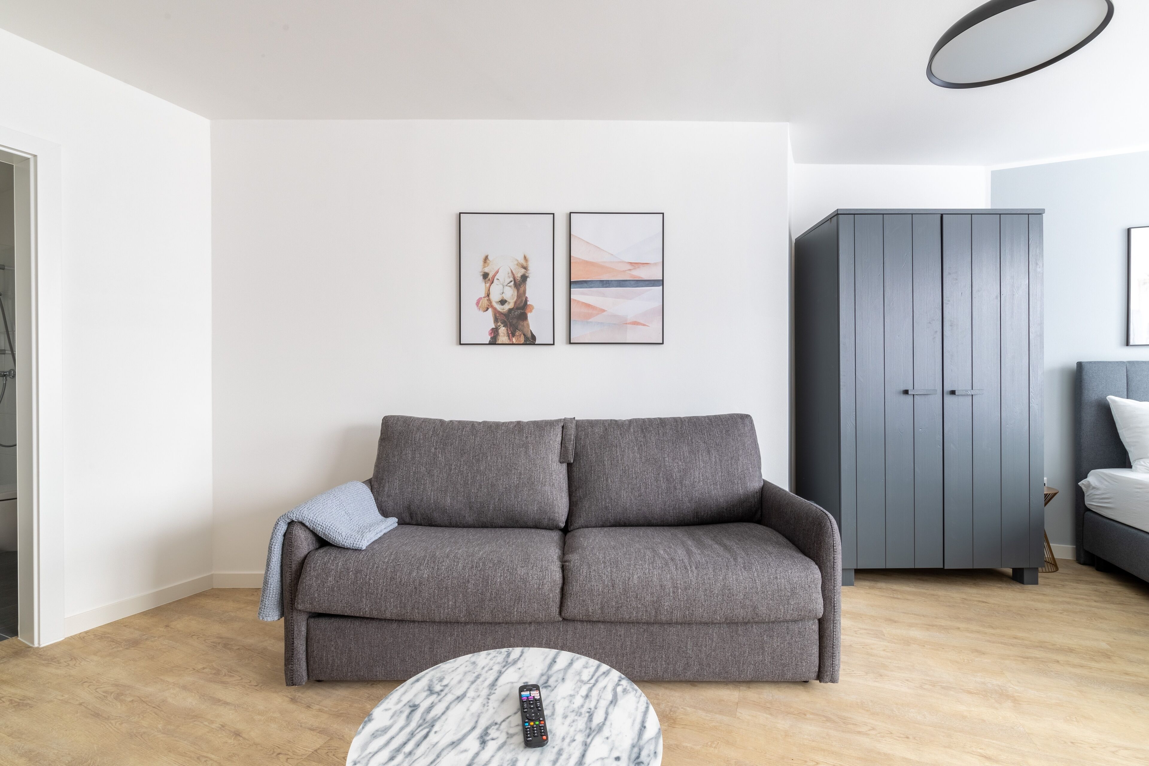 Een moderne woonkamer met een grijze bank, een marmeren salontafel en een grijs kastje.