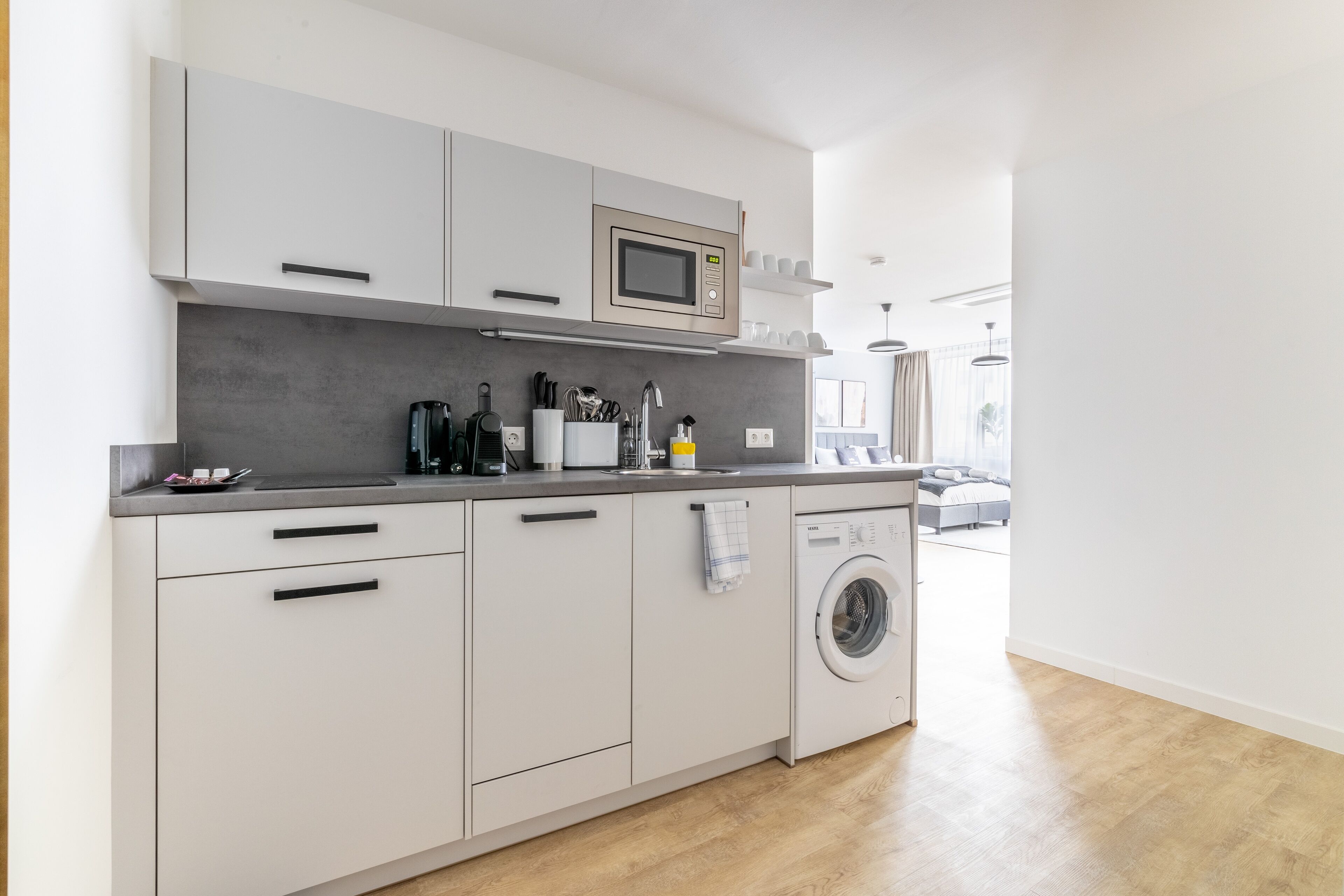Een moderne keuken met een ingebouwde magnetron, vaatwasser en wasmachine.