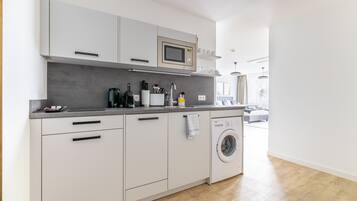Een moderne keuken met een ingebouwde magnetron, vaatwasser en wasmachine.