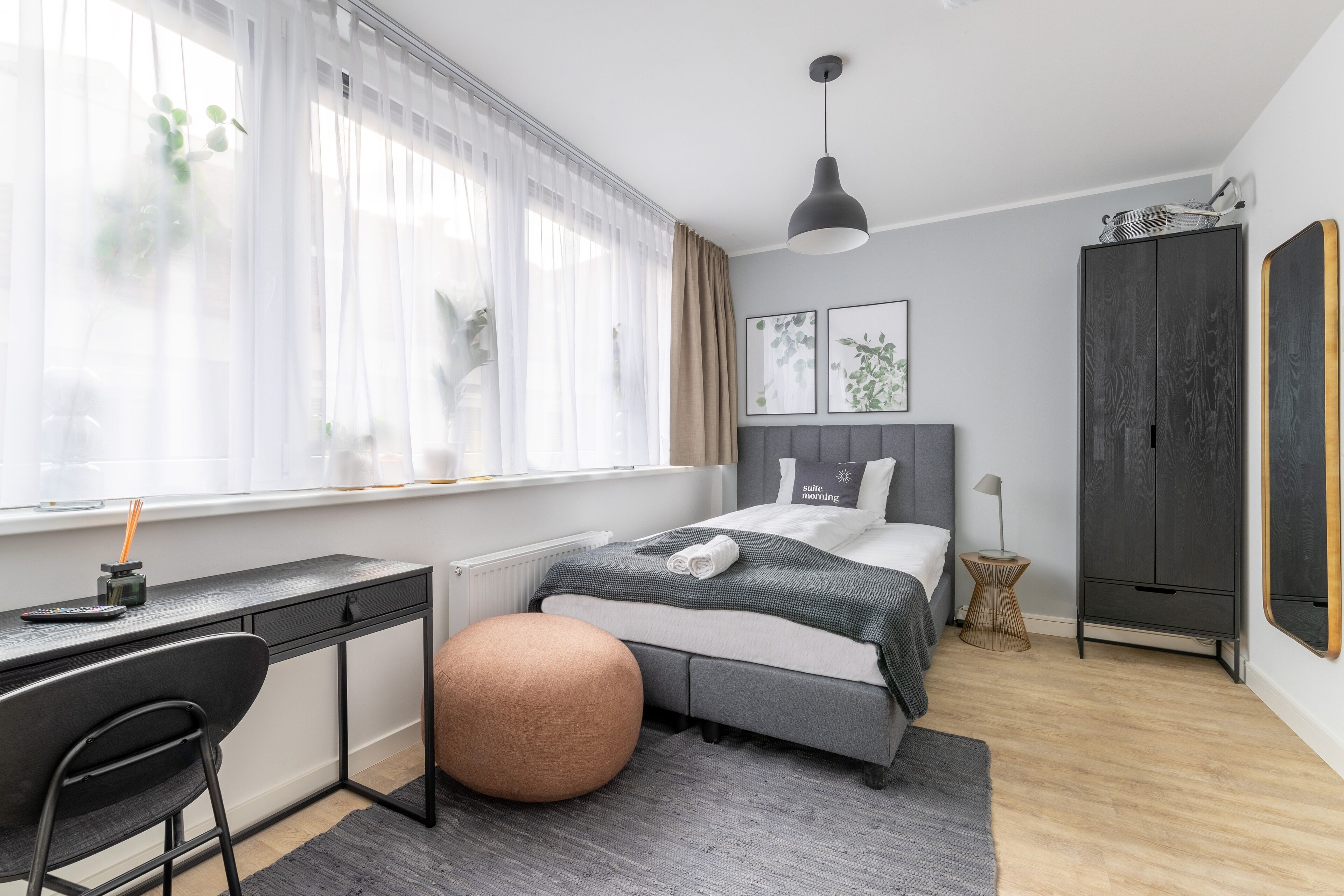 Un dormitorio moderno con cama, mesita de noche y un escritorio con silla.
