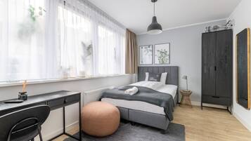 Un dormitorio moderno con cama, mesita de noche y un escritorio con silla.