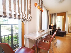 A dining area with a long table, chairs, and a view of greenery outside.