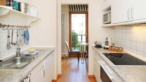 A narrow kitchen with a sink, stove, and cabinets. There is a window with a view of the outside. - Apartment with 1 bedroom and balcony (Seebad Heringsdorf)