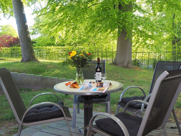 Uma mesa ao ar livre com uma garrafa de vinho, dois copos e um buquê de flores.